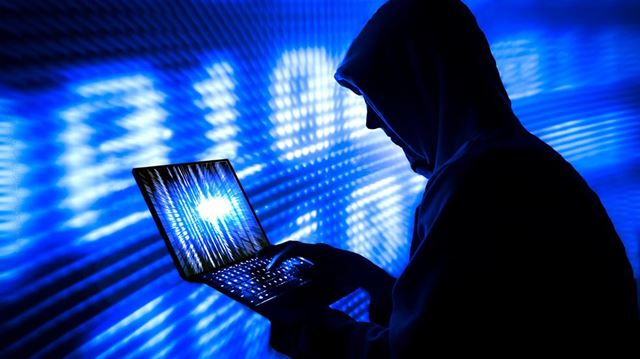 Online scams man typing keyboard hood
